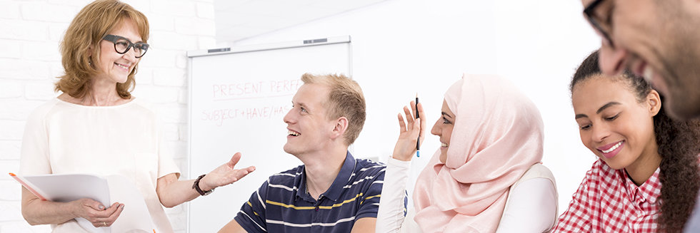Laughing and happy participants of a language course with their teacher in classroom